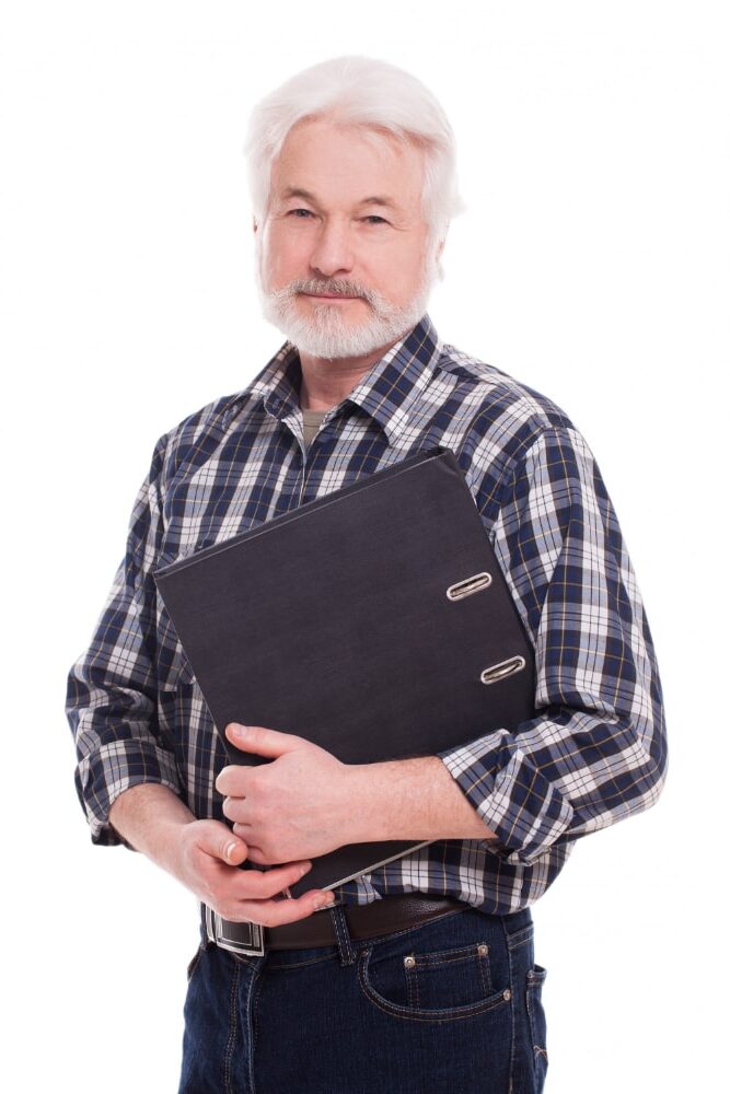 An old man holding his notebook while smiling at the camera